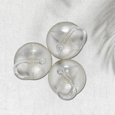 Two transparent suction hooks with strong hold on a bathroom tile wall.